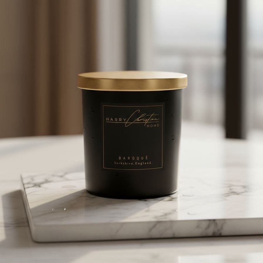Black candle with gold lid on a marble surface by Harry Christian Home