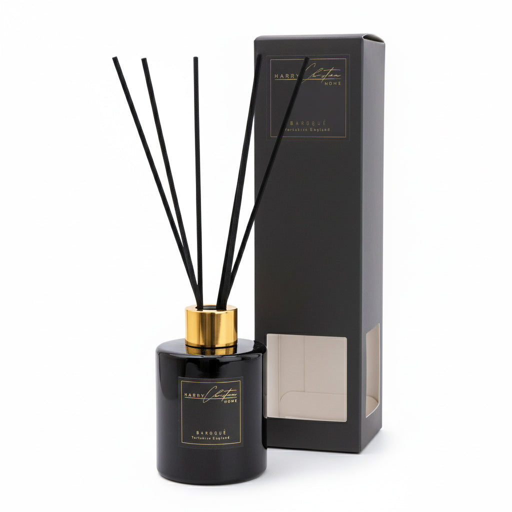 Black diffuser bottle with gold cap and black sticks, next to its packaging on a white background. Harry Christian Home Baroque Black And Gold Reed Diffuser With Packaging 